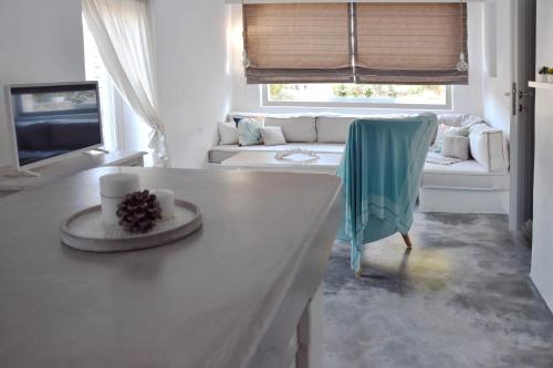 a white living room with a table and a couch at Koukounari Cottage Apartment Paros in Naousa