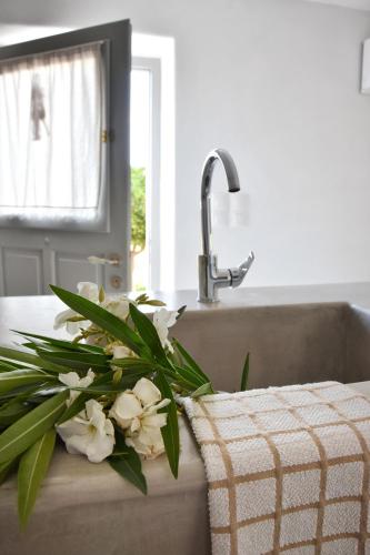 a kitchen counter with a sink with white flowers at Koukounari Cottage Apartment Paros in Naousa