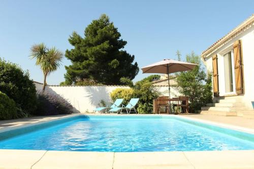 une piscine avec deux chaises et un parasol dans l'établissement Oleander- Spacious Villa with Private Pool & Garden Sleeps 6, à Puimisson