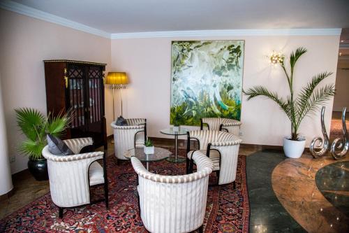 a living room with chairs and a table and a painting at Hotel Admiral am Kurpark in Baden
