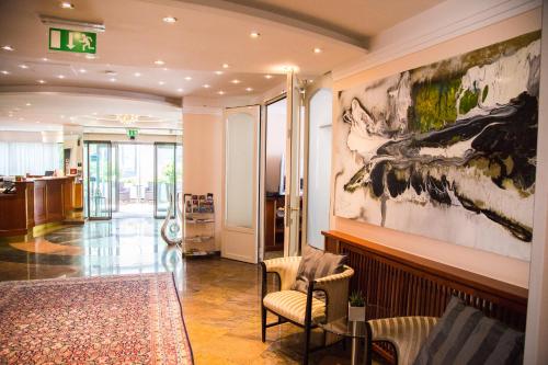 a lobby with a chair and a painting on the wall at Hotel Admiral am Kurpark in Baden