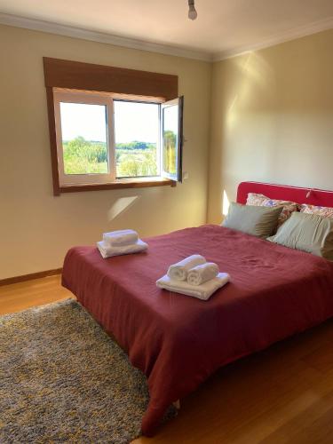 a bedroom with a red bed with towels on it at Welcoming house with terrace and garden in Barra de Mira in Areão