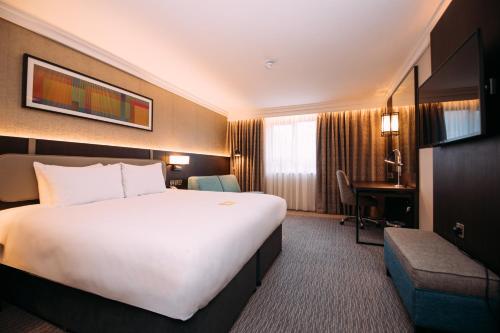 um quarto de hotel com uma grande cama branca e uma secretária em Crowne Plaza - Belfast, an IHG Hotel em Belfast
