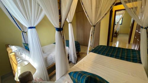 a bedroom with two beds with drapes at Kitiko residence Hotel in Entebbe