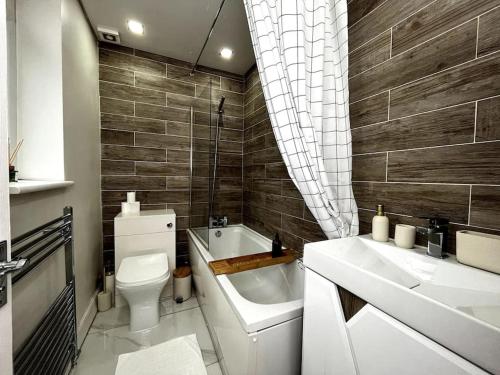 a bathroom with a toilet and a sink and a tub at Tranquil 3 Bed Oasis with Parking in Worsley