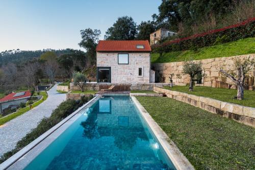 a swimming pool in front of a stone house at Javardo - Family House - Douro in Penha Longa