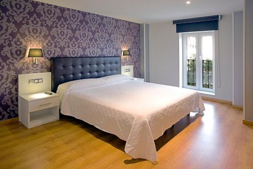 a bedroom with a large bed and a purple wall at Apartamentos Spa Villa Pasiega in Hoznayo