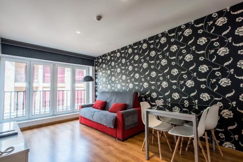 a living room with a red couch against a black wall at Apartamentos Spa Villa Pasiega in Hoznayo