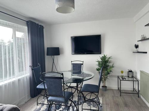 sala de estar con mesa, sillas y TV en Sunny Apartment In Cheltenham en Cheltenham