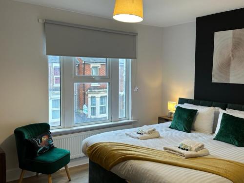 a bedroom with a bed with a green chair and a window at 3 Bed Chill Glouc Free Parking in Gloucester