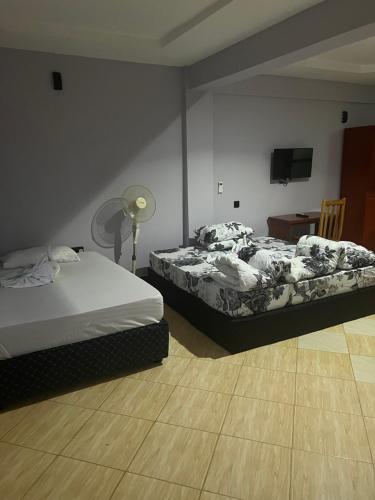 1 dormitorio con 2 camas, mesa y lámpara en luxpalacehotel limited, en Moshi