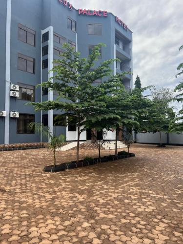 un edificio con dos árboles delante de él en luxpalacehotel limited, en Moshi