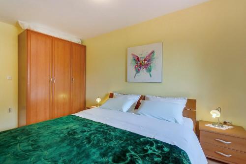 a bedroom with a large bed with a green blanket at House ROSSELLA with cozy apartment and rooms close to the beach in Nerezine