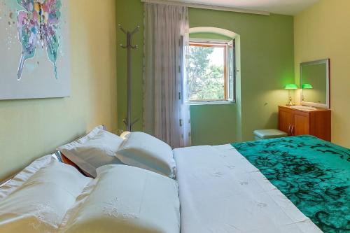 a bedroom with a bed with white sheets and a window at House ROSSELLA with cozy apartment and rooms close to the beach in Nerezine
