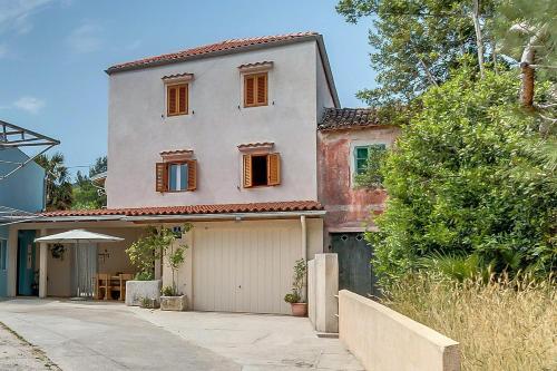 a house with a garage in front of it at House ROSSELLA with cozy apartment and rooms close to the beach in Nerezine