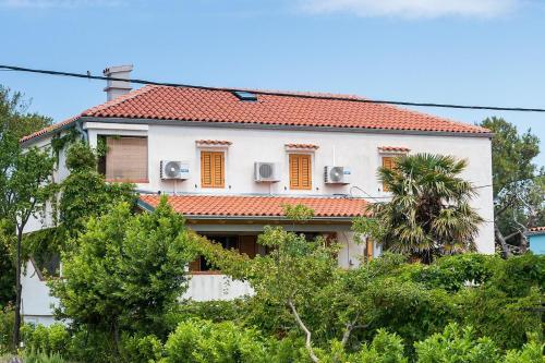 a white house with a red roof at House ROSSELLA with cozy apartment and rooms close to the beach in Nerezine