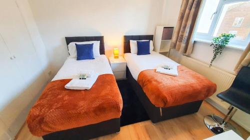 two beds in a room with blue and orange sheets at Cheerful 4-bedroom House in Cheltenham