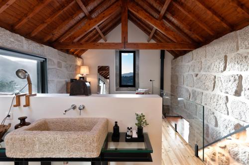 a bathroom with a large tub in a stone wall at Javardo - Family House - Douro in Penha Longa