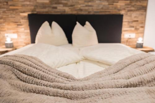 a bed with white pillows and a blanket at Aparthotel Herzblick GmbH in See
