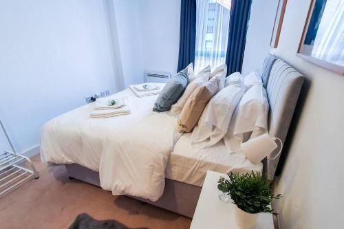 a bedroom with a bed with white sheets and pillows at Lovely Flat In Kiln Close With Free Parking in Gloucester