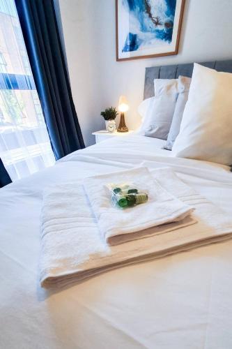 a white bed with a pile of towels on it at Lovely Flat In Kiln Close With Free Parking in Gloucester