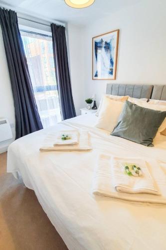 a bedroom with a large white bed with towels on it at Lovely Flat In Kiln Close With Free Parking in Gloucester