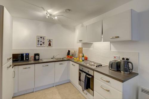 a white kitchen with white cabinets and a sink at Lovely Flat In Kiln Close With Free Parking in Gloucester
