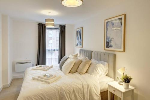 a white bed in a room with a window at Lovely Flat In Kiln Close With Free Parking in Gloucester