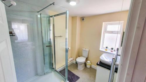 a bathroom with a glass shower and a toilet at White Jasmine In Stroud in Stroud