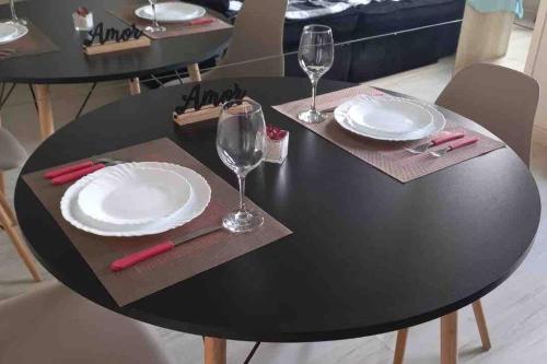 a black table with two white plates and wine glasses at Apto Lindo/Aconchegante perto da UEL/bares/ centro in Londrina