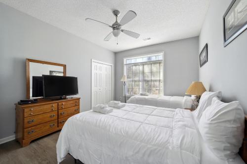 a bedroom with a white bed and a flat screen tv at Riverside Relaxation – Golf, Beach & More - Little River, South Carolina in Little River