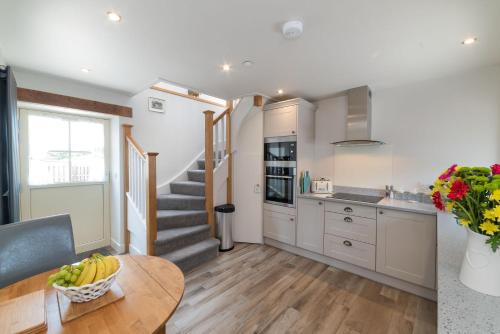 a kitchen with a staircase and a table with a bowl of bananas at Ewe Bach Cottage in Llanasa