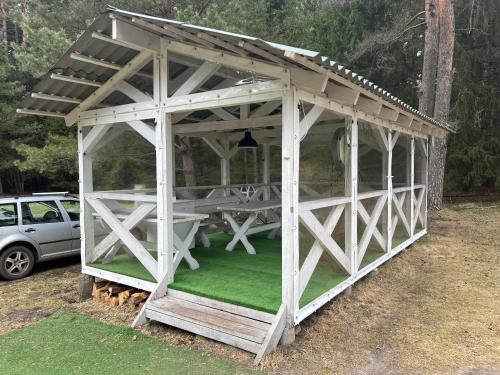 a white gazebo with a green lawn at Miškas Arjola in Kaltanėnai