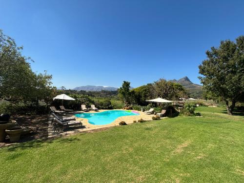 - une piscine dans une cour avec une pelouse dans l'établissement In the Vine Country Manor & Spa, à Stellenbosch