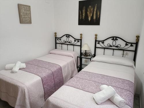 two beds in a room with white and purple at Apartamento Candari Playa en Cadiz in Cádiz