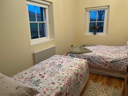 two beds in a room with two windows at Dunnaglea Cottage, Ballintoy in Ballintoy