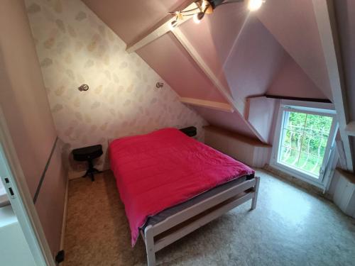 una piccola camera da letto con letto rosso in mansarda di Gîte les Yards a Yffiniac