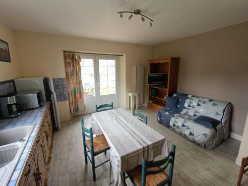 eine Küche und ein Wohnzimmer mit einem Tisch und einem Bett in der Unterkunft Gîte les Yards in Yffiniac