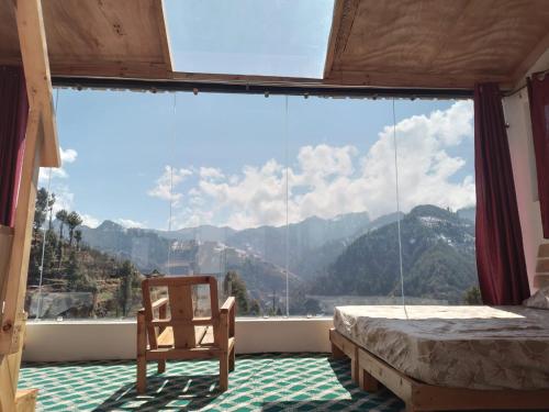 1 dormitorio con ventana grande, cama y silla en Stargazing Glass Lodge Himachal Pradesh Thachi en Mandi