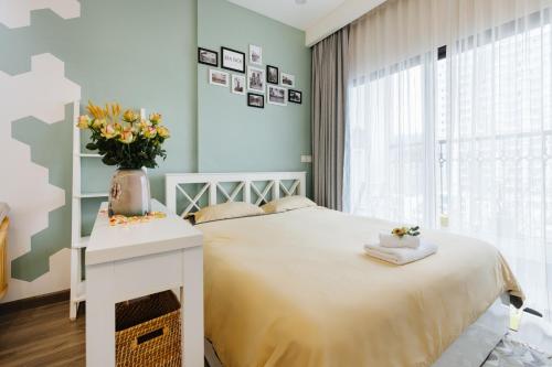 a bedroom with a bed and a vase of flowers on a table at Pearland -D'Eldorado Apartment in Hanoi