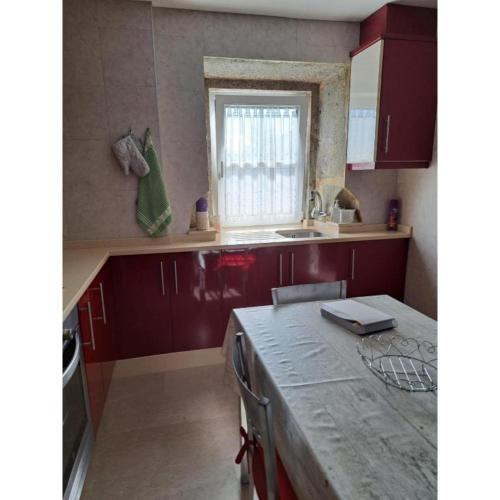 a kitchen with red cabinets and a sink and a window at Meraki in Finisterre