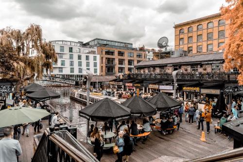 a group of people sitting at tables on a pier next to a river at Camden Town Self Check-in Luxury Rooms in London