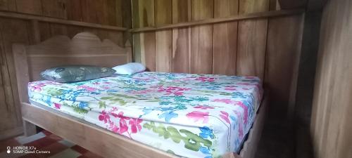 a bed with a pillow on it in a wooden room at Lodging and Adventure in Soposo