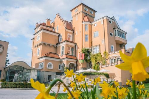 un grand bâtiment avec des fleurs jaunes devant lui dans l'établissement Hotel Schloss Mönchstein, à Salzbourg