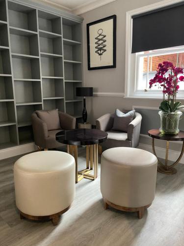 a living room with two white stools and a table at One Warwick Park Hotel in Royal Tunbridge Wells
