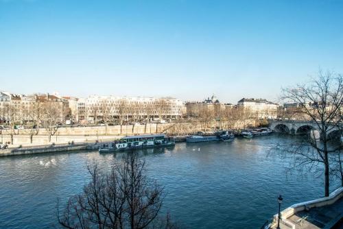 a river with boats and a bridge and buildings at Ile Saint Louis & Direct River Views - CityApartmentStay in Paris