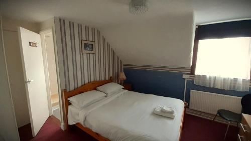 a bedroom with a large white bed with a window at The Langtry Hotel in Clacton-on-Sea