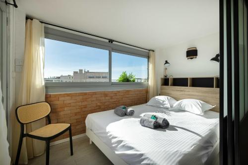 Agence des Résidences - Plein centre de Cannes في كان: غرفة نوم بسرير وكرسي ونافذة
