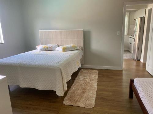 ein Schlafzimmer mit einem Bett mit einer weißen Decke und einem Teppich in der Unterkunft Blumen Espaço "piscina privativa' in Blumenau