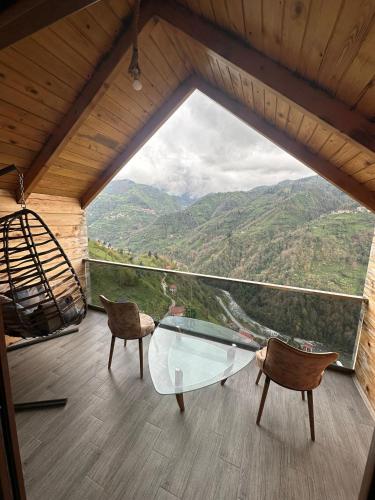 a glass table and chairs in a room with a view at Peruma otel bungalov in Çamlıhemşin